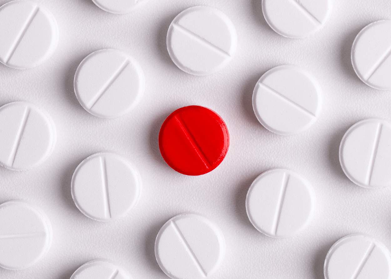 Pastillas de color blanco rodeando una pastilla de color rojo