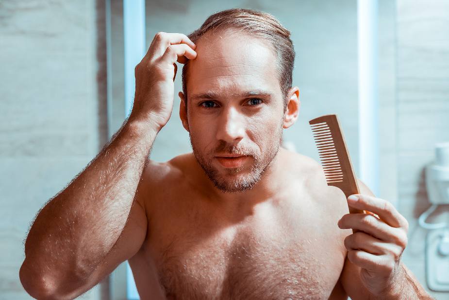 Hombre mirándose en el espejo si tiene caída anormal del cabello