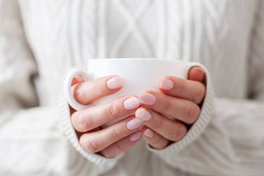 mujer sostiene una taza de cafe en las manos