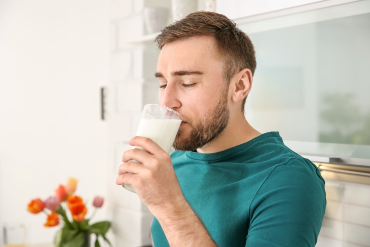 Mann trinkt Milch und nimmt Kalzium für die Haare auf